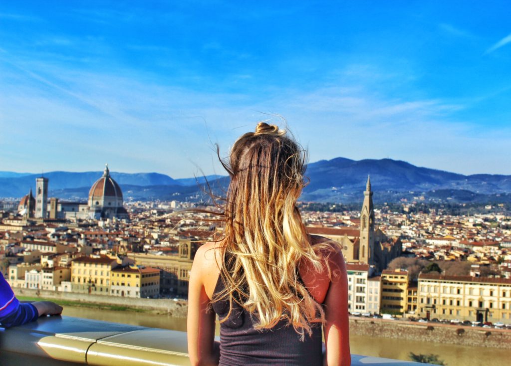 Blonde girl looking out over Florence Italy. Beautiful Italian cityscape. travel research on pickpockets will help you survive italy