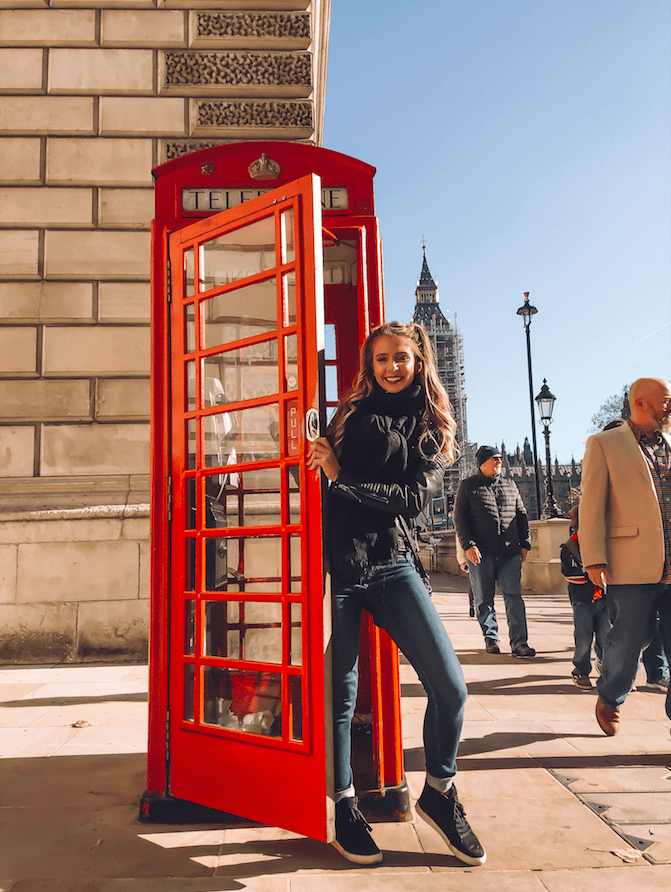 cute girl at telephone book in london smiling wearing leather jacket and jeans